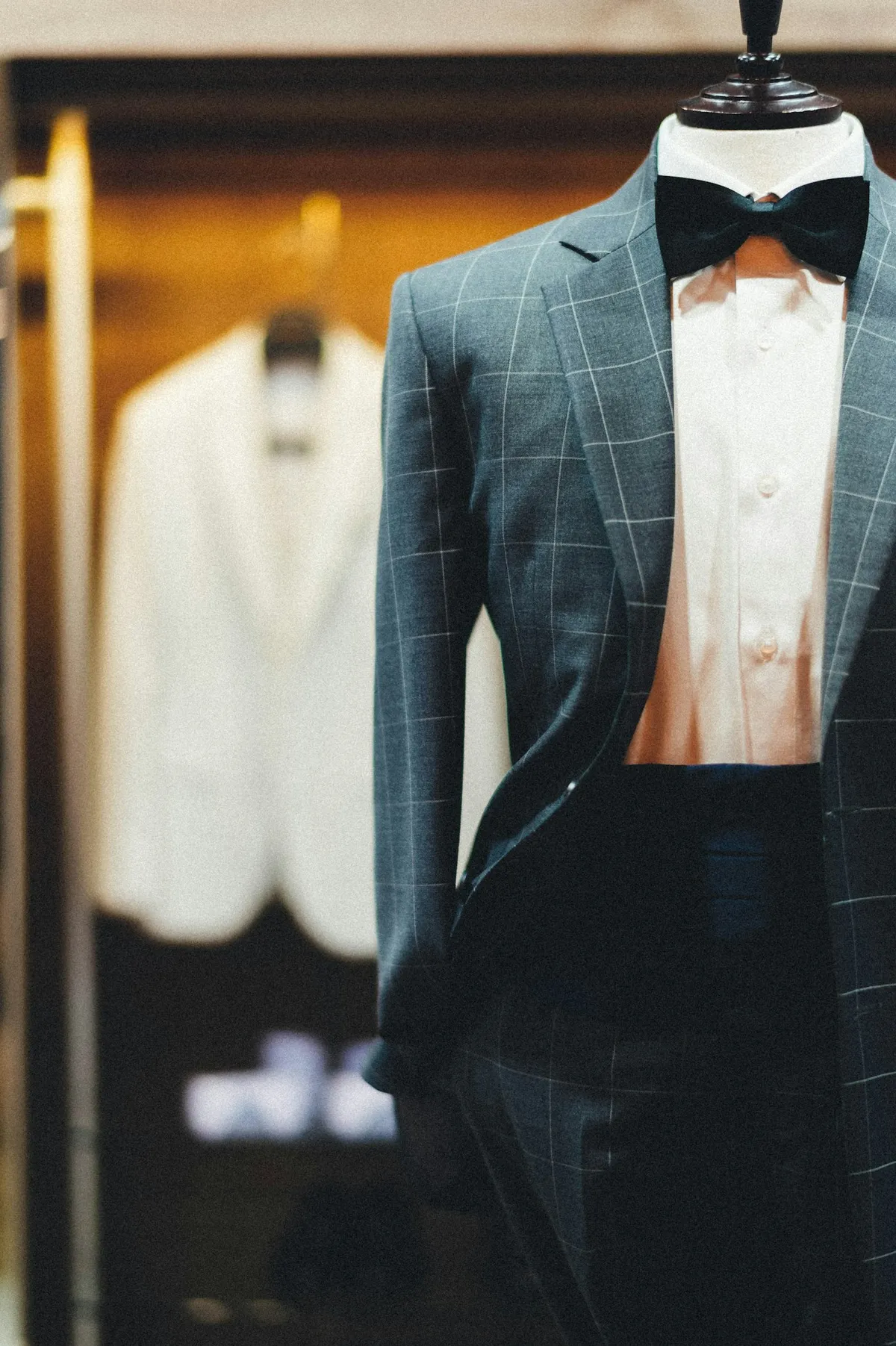 Vitrină showroom cu costum în carouri și papion, prezentare pe manechin